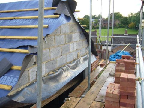 Builders work on the cross gable block and brickwork